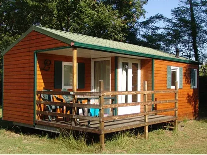 Mobil-home en bois orangé avec terrasse couverte et finitions vertes