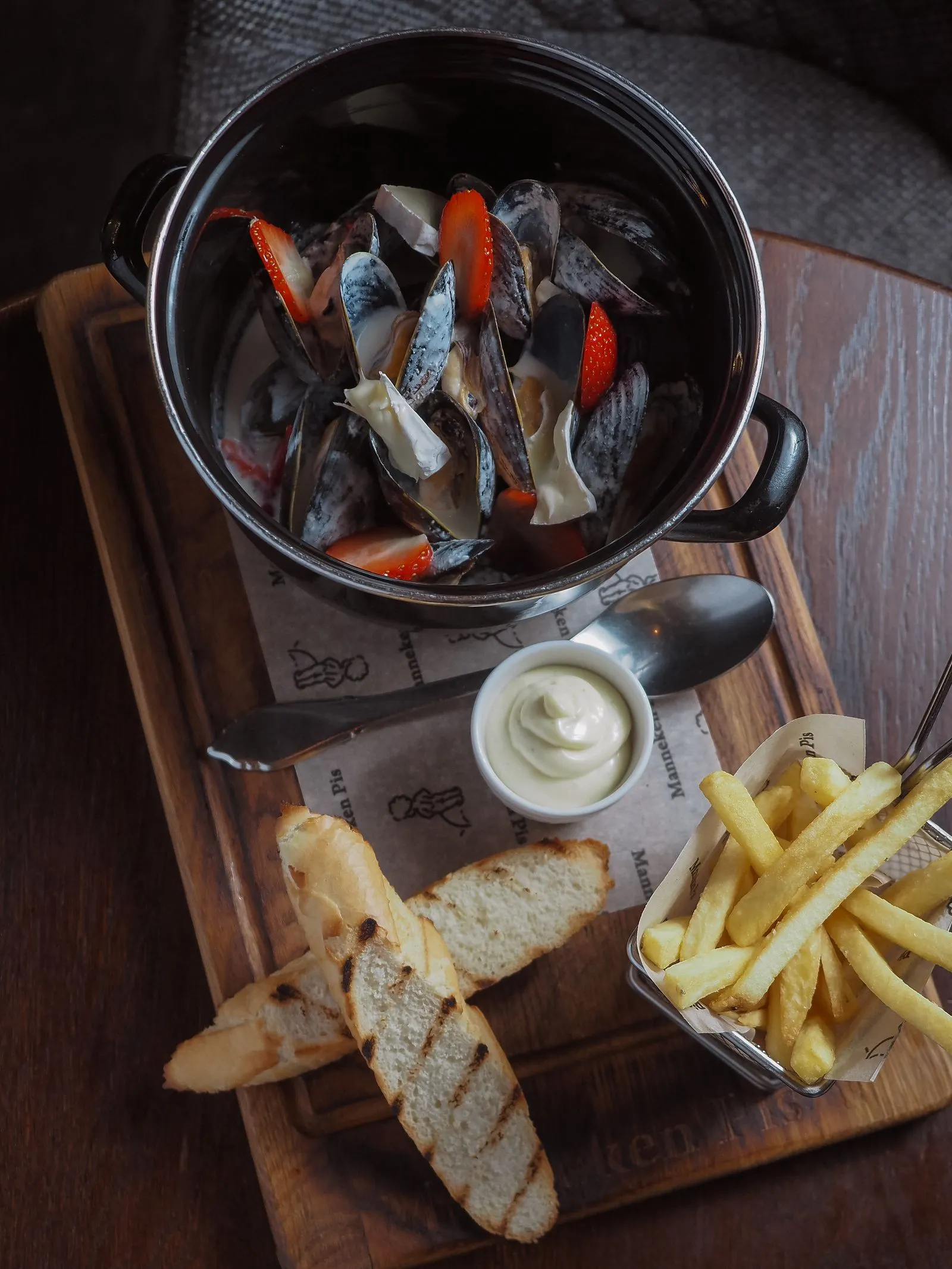 Moules servies dans une cocotte avec des frites et des tranches de pain grillé